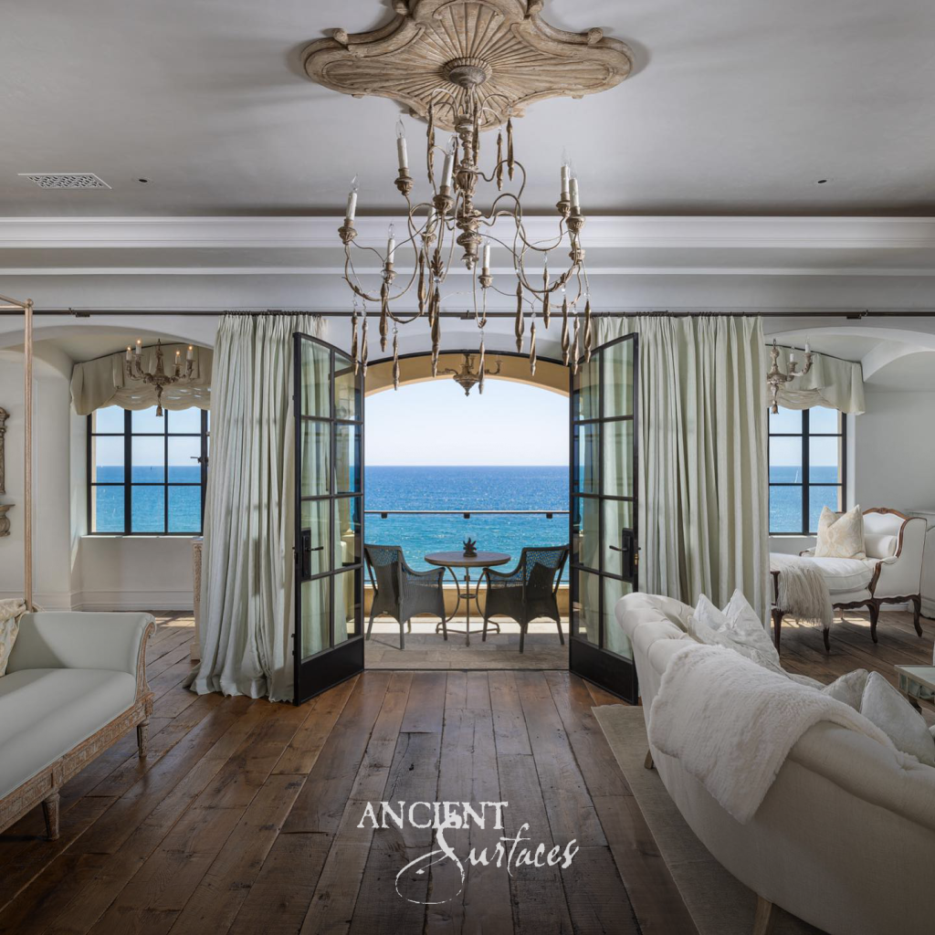 Ocean facing sitting room with wide plank wood floors and arched doors opening onto a balcony above the water